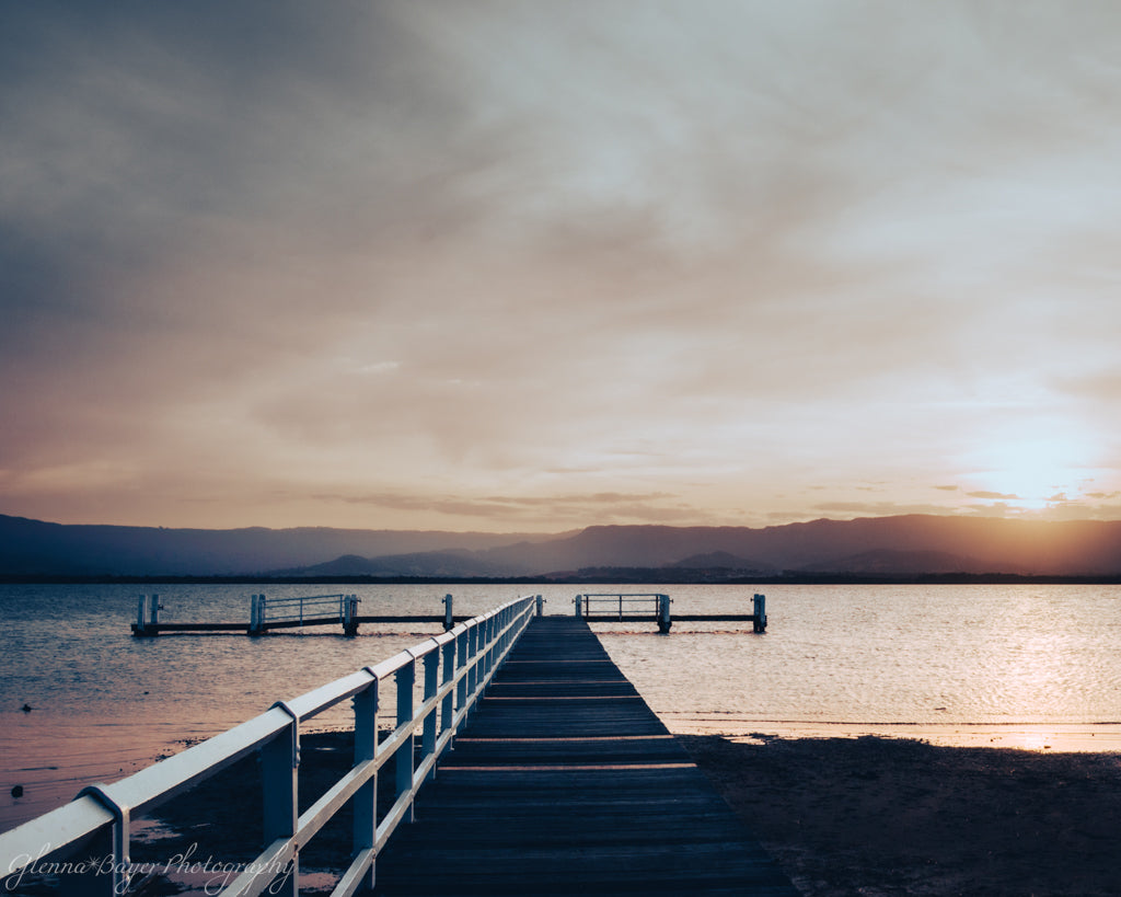 Dock leading into lake during sunset