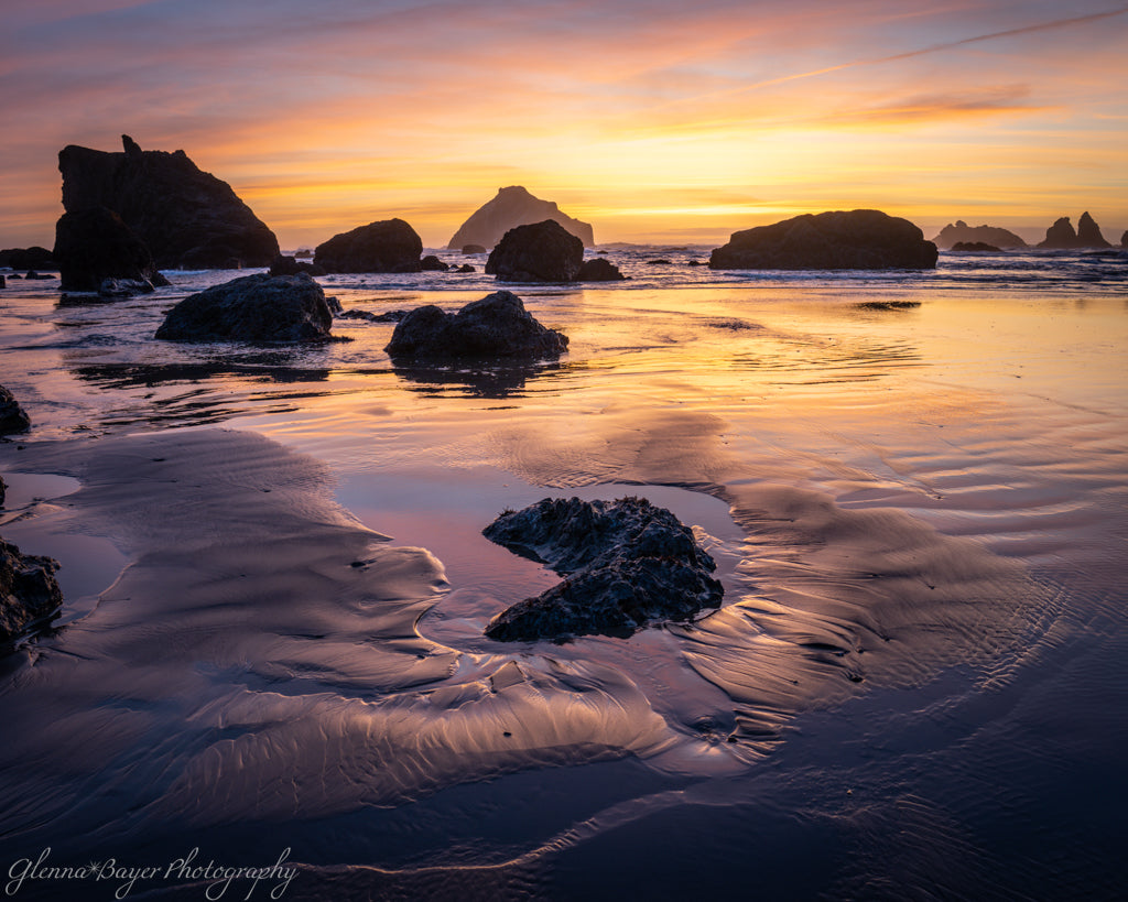 dramatic purple and yellow sunset on rocky beach