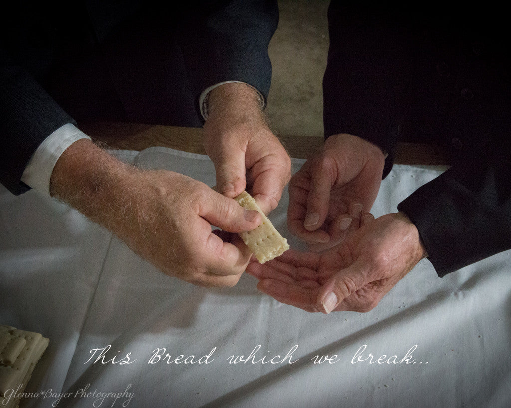 Men's hands breaking communion bread with scripture verse