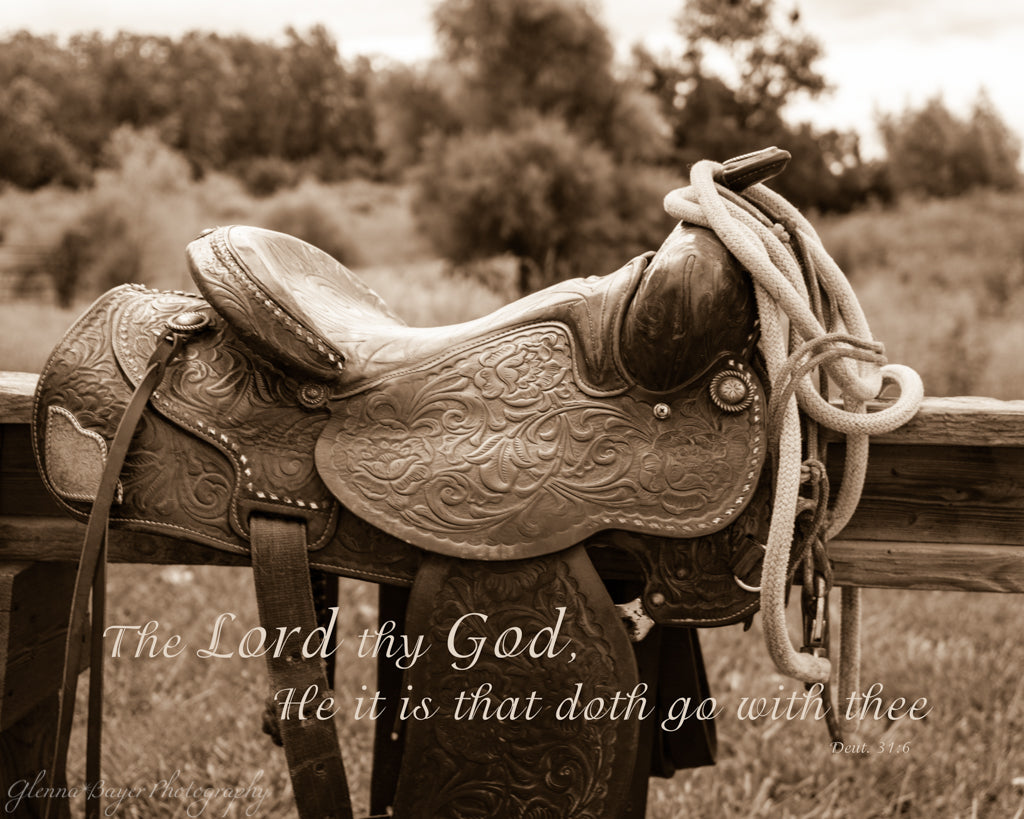 Western saddle on fence with scripture verse