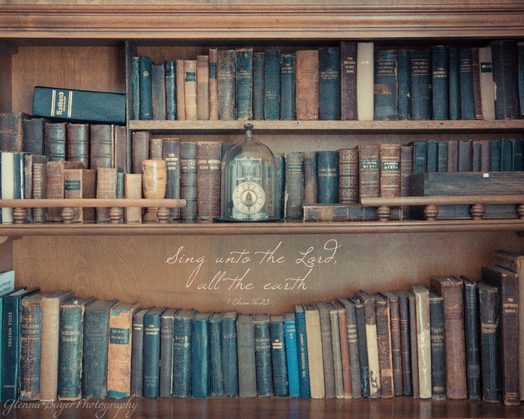 Old, vintage hymn books on shelf with scripture verse