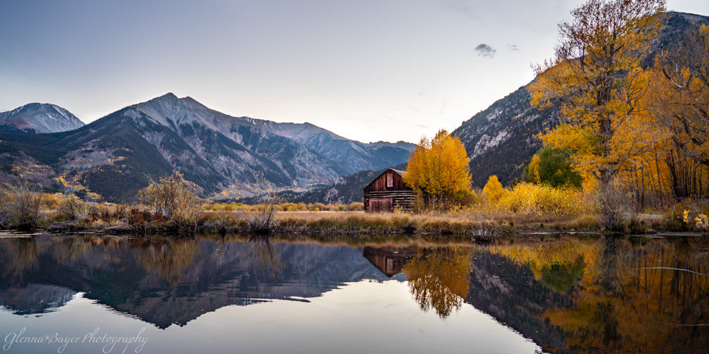Cabin behind pond in front of mountains
