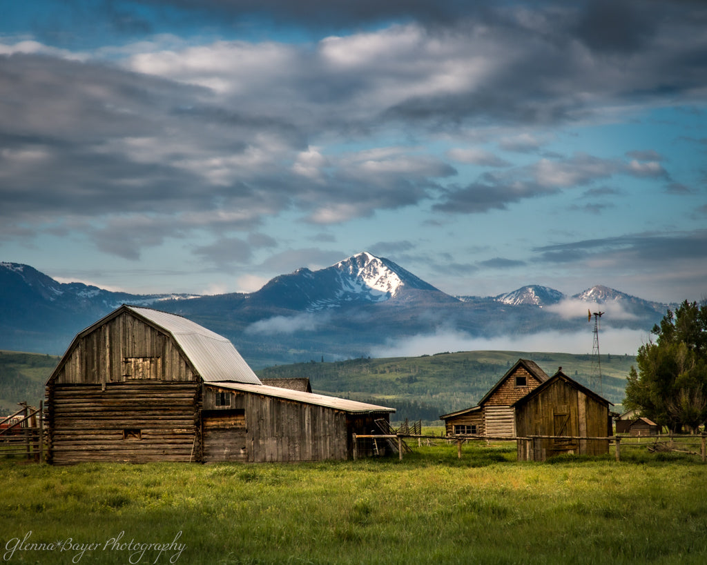 Old wooden barns with snow capped mountain in background