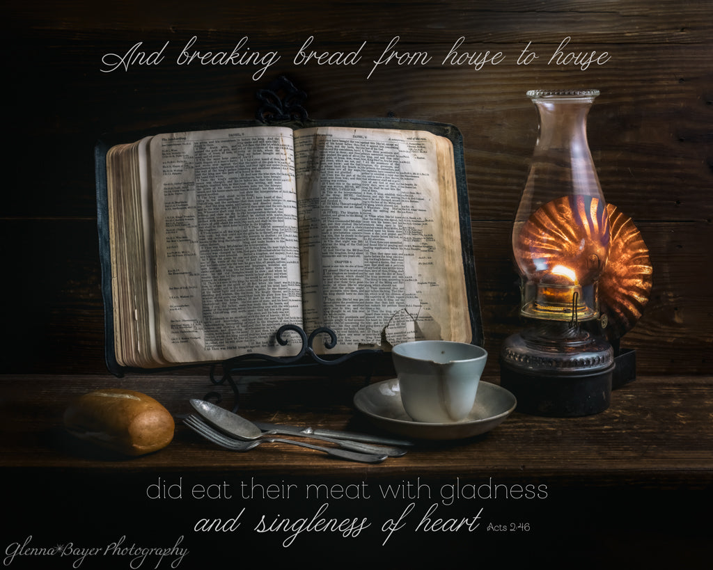 Still life scene with an open bible, cup, spoon, bread, and oil lamp on a wooden surface.