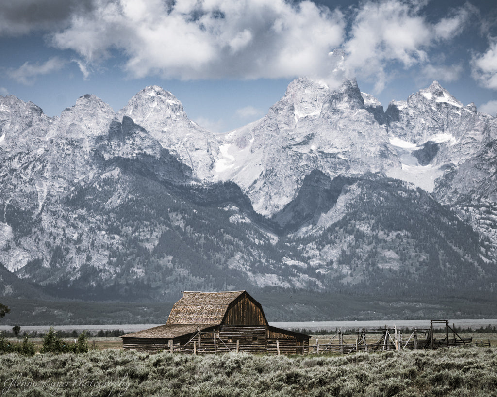 Wooden barn in a field with snow-capped Teton mountains in the background