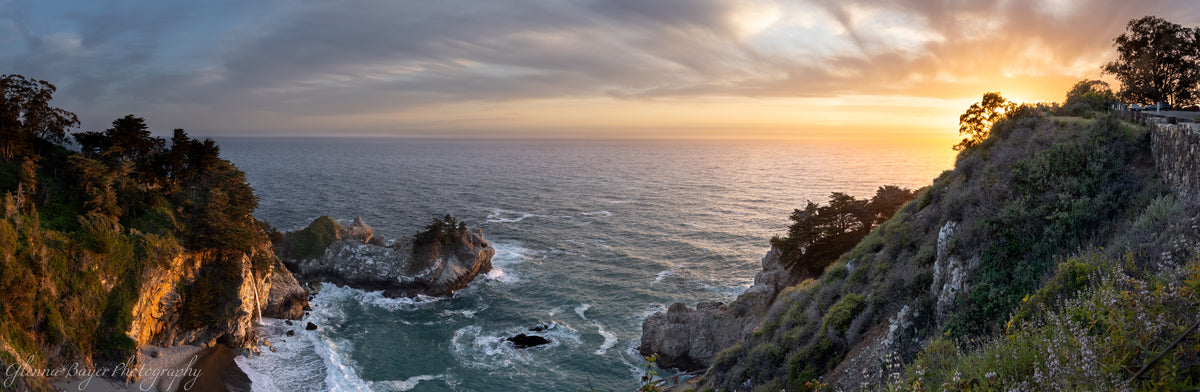 Sunset over a coastal landscape with cliffs and ocean.