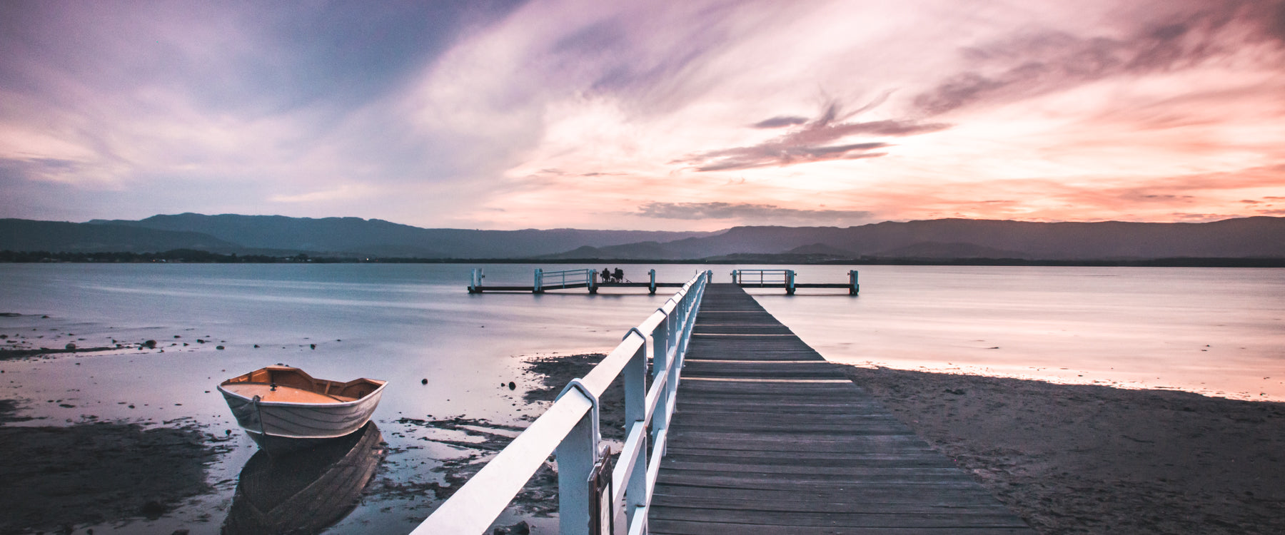 Boat and dock on lake at sunset