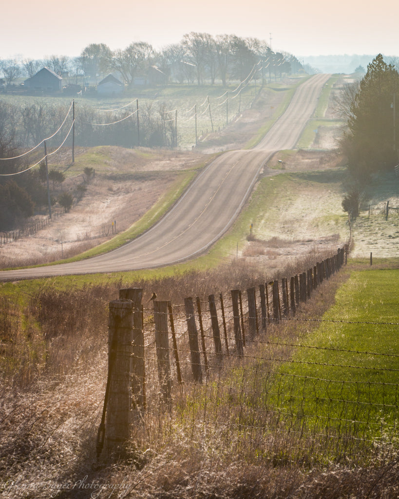 Road and fence through the rolling hills of Kansas