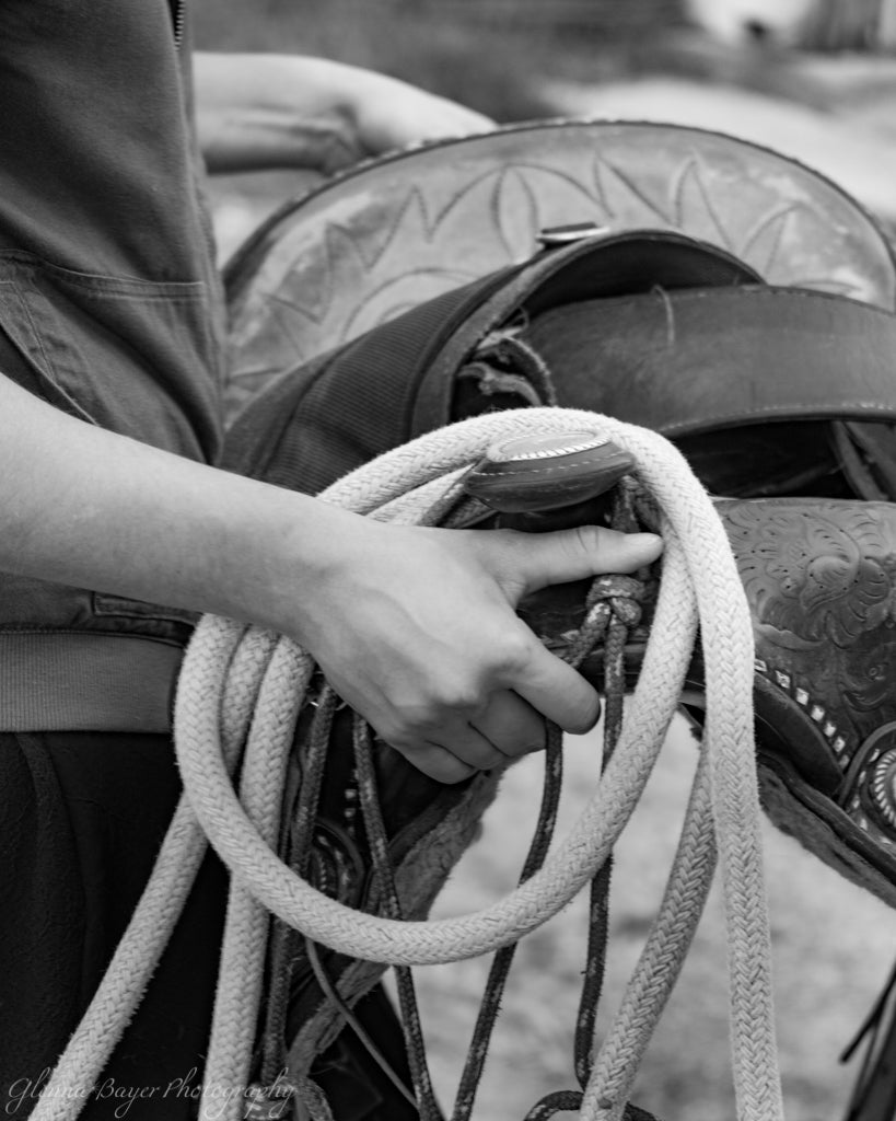 Woman carrying western saddle and lead rope