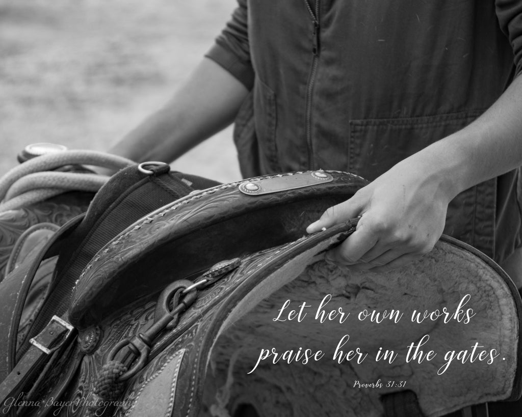 Woman carrying western saddle with scripture verse