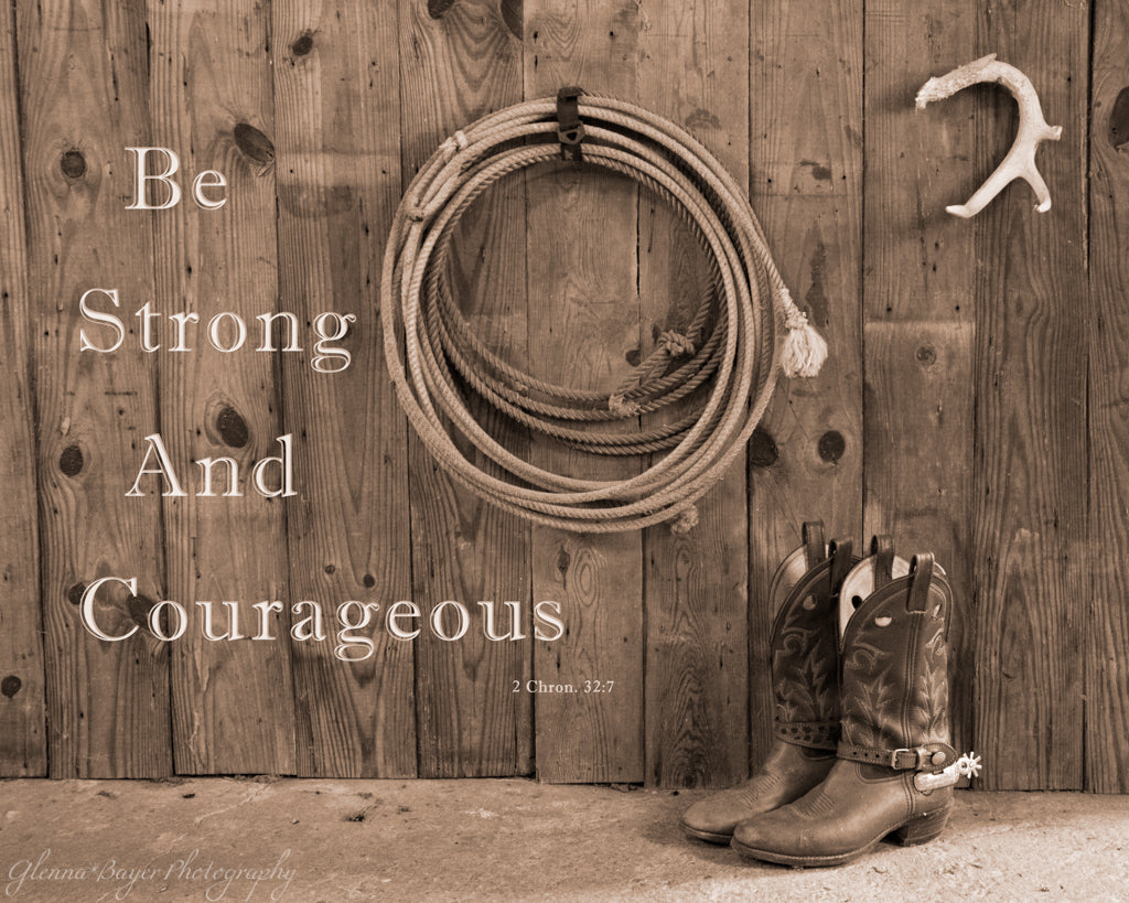 Cowboy boots and lasso rope against wooden barn wall with scripture verse