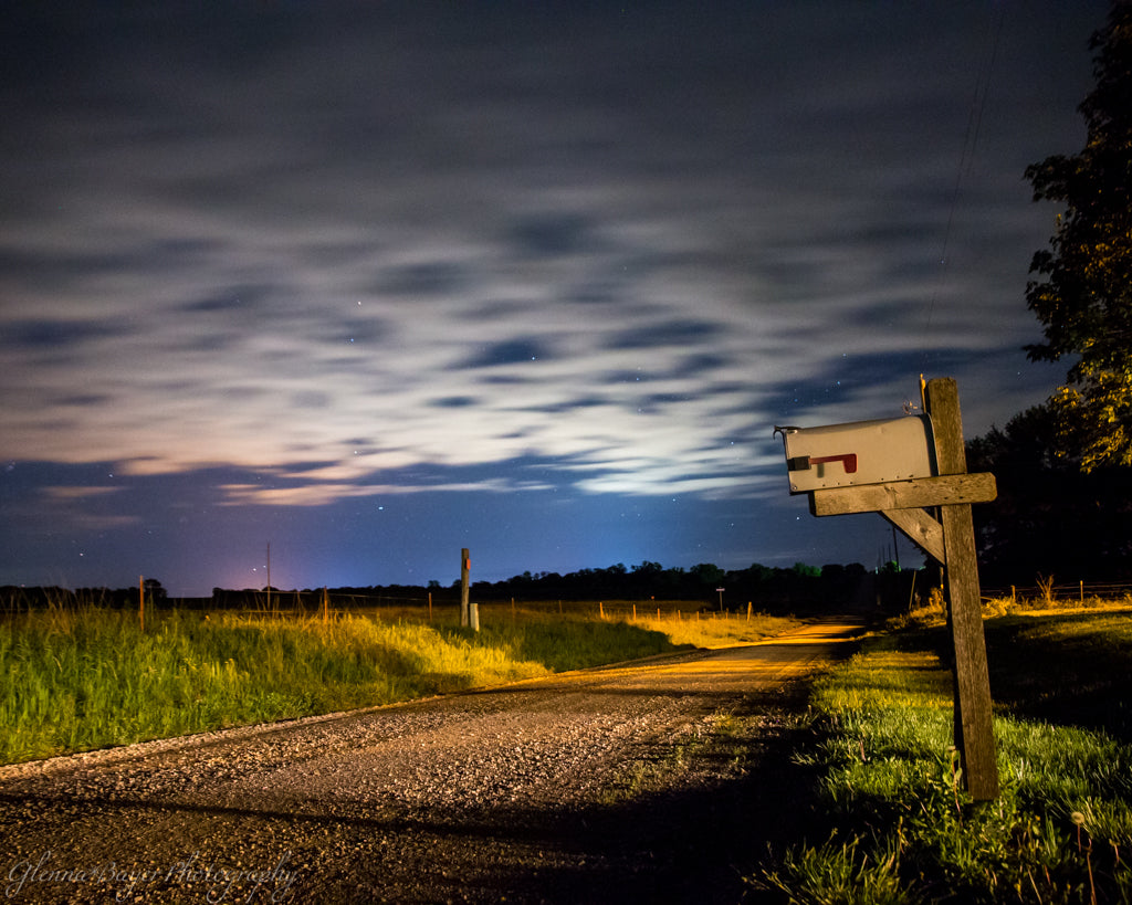 Mailbox beside gravel road and a cloudy night sky in Kansas