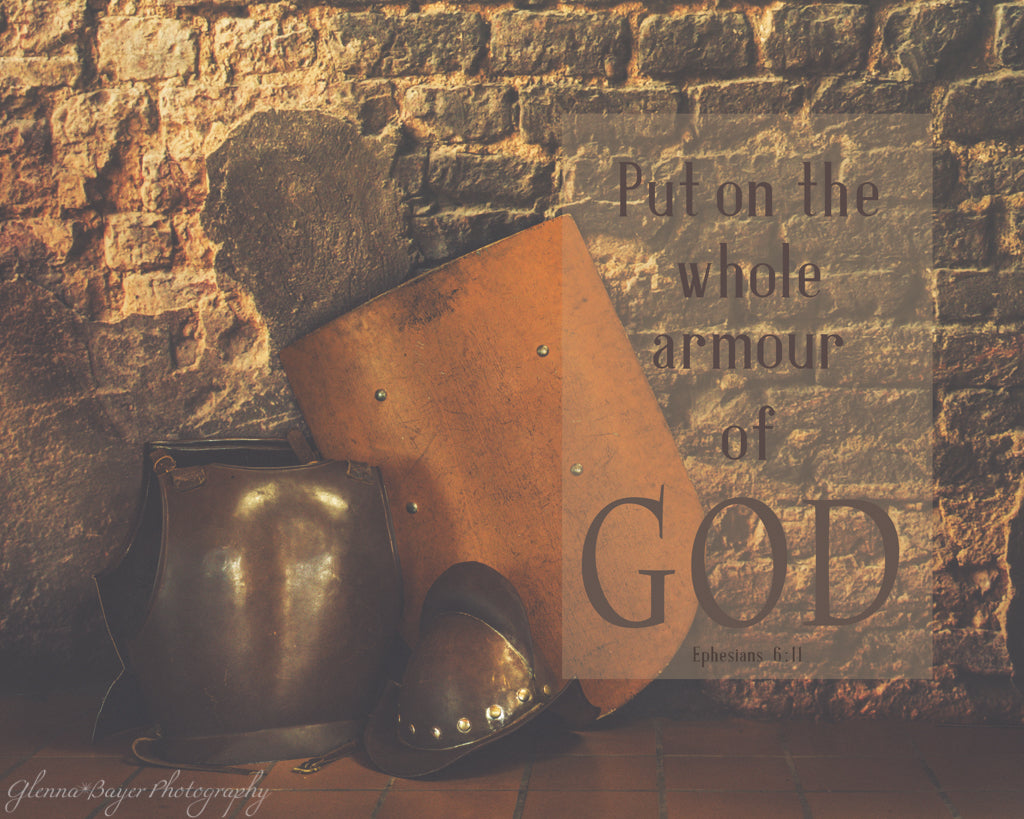 Shield, breastplate, and helmet leaning against brick wall with scripture verse about amour of God