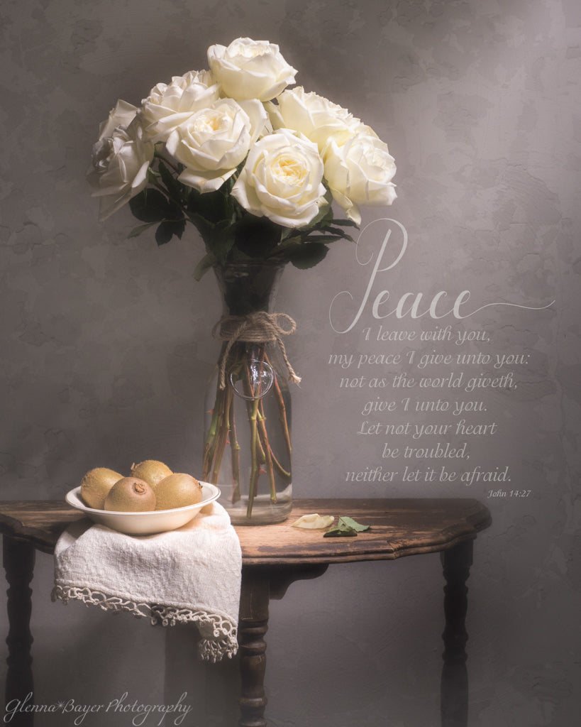 Still life of a white rose bouquet, kiwis in bowl, and white cloth on end table with scripture verse