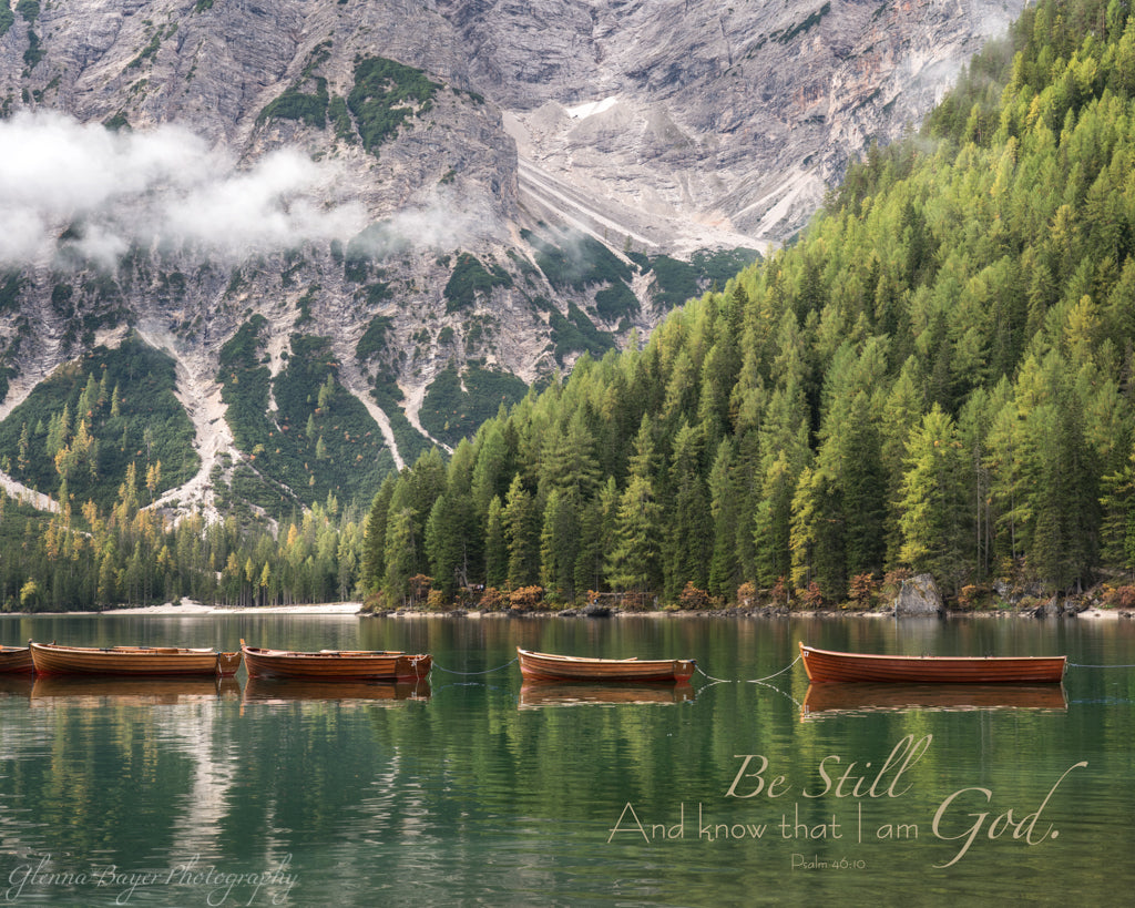 Canoes lined across Lake Braies in Dolomites, Italy with scripture verse