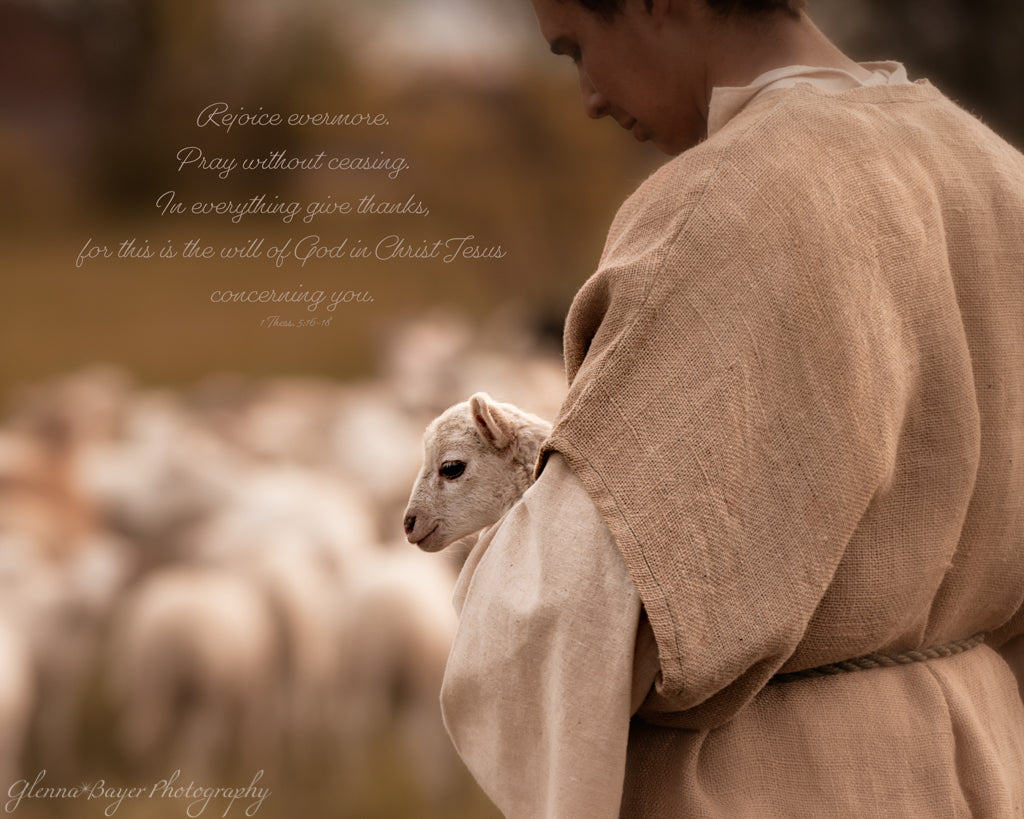 Shepherd holding lamb near flock of sheep with bible verse