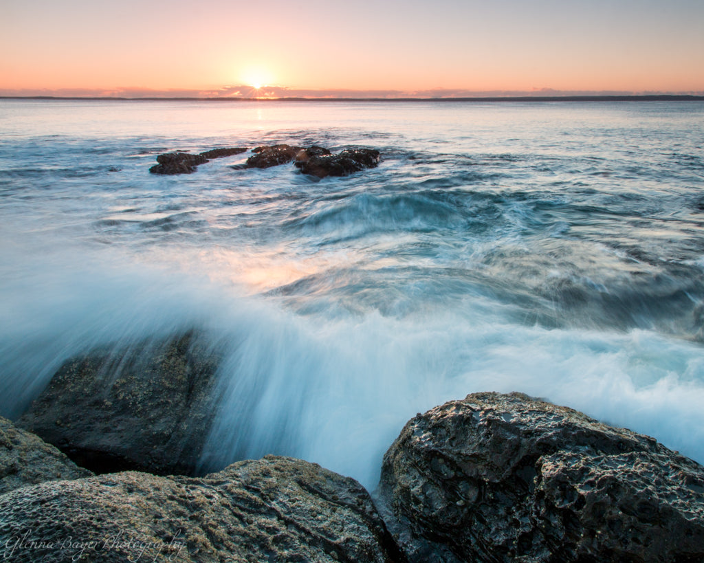 Sunrise over Jervis Bay and waves crashing over rocks in Australia