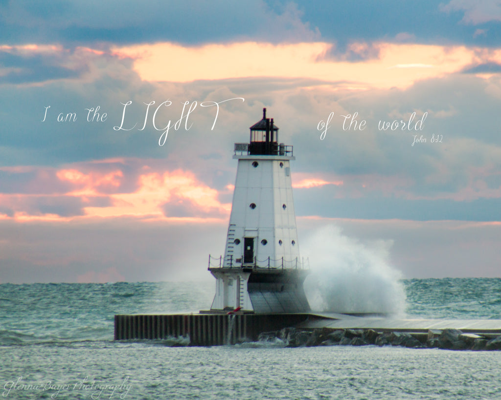 Wave crashing into Ludington Lighthouse on Lake Michigan during pink sunset with scripture verse