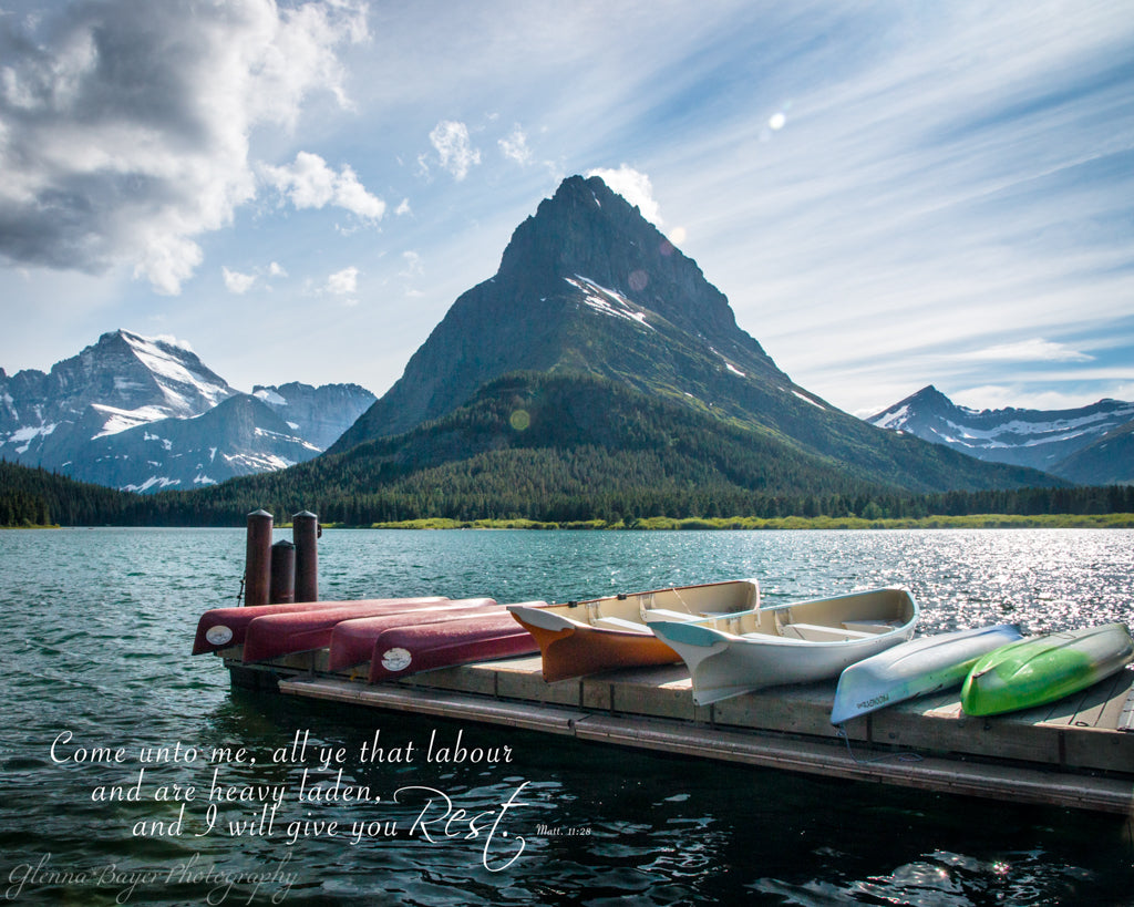 Canoes on dock at Lake McDonald in Glacier National Park with scripture verse