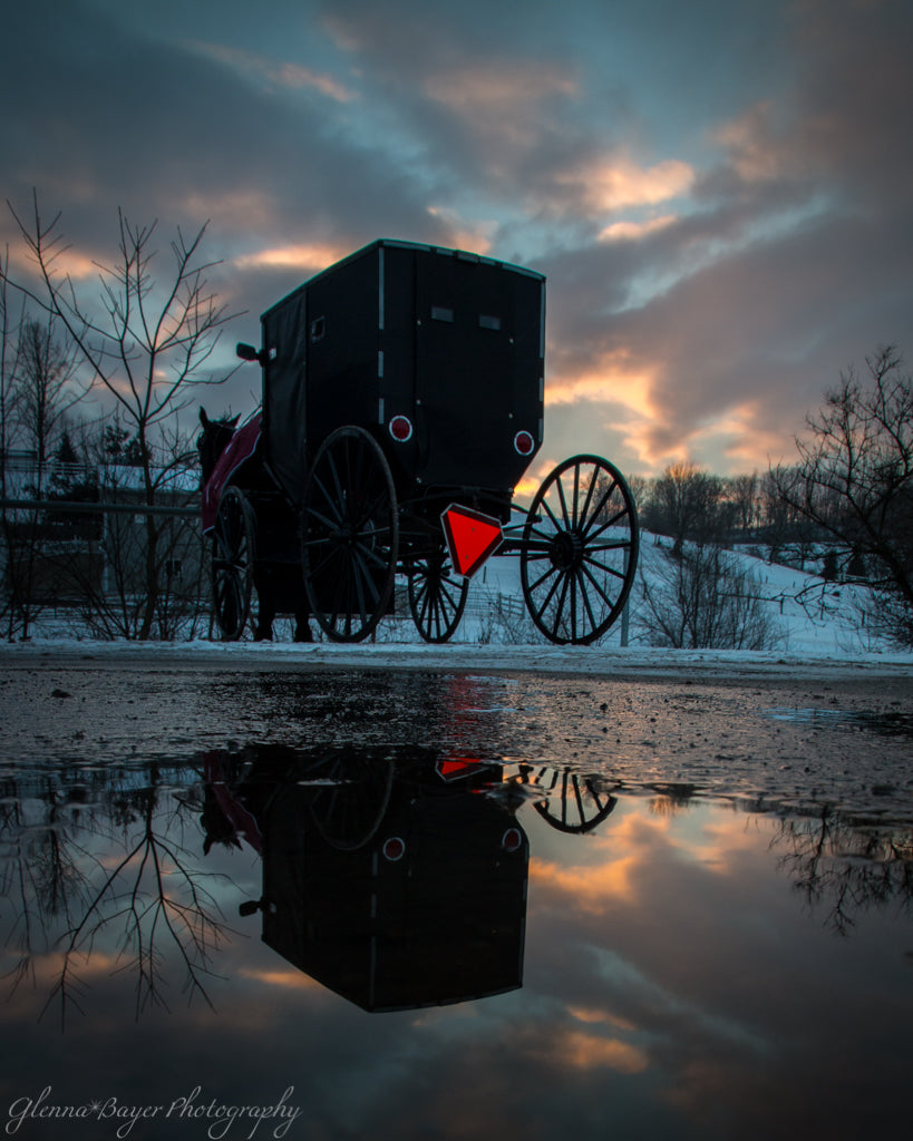 Amish horse and buggy at sunset with blue clouds and sky.