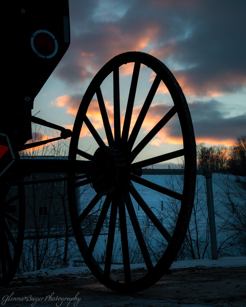 Silhouette of Amish buggy wheel during sunset