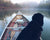 Black dog in old canoe on pond during foggy morning