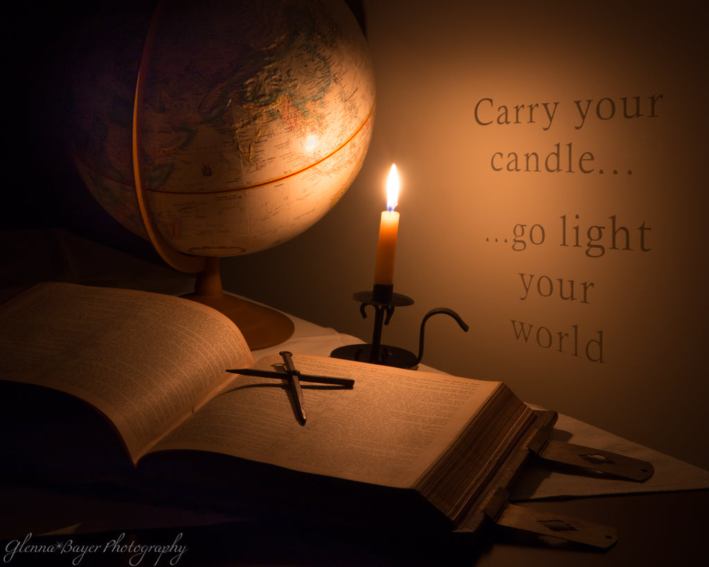 Cross lying on open bible with globe and candle still-life  