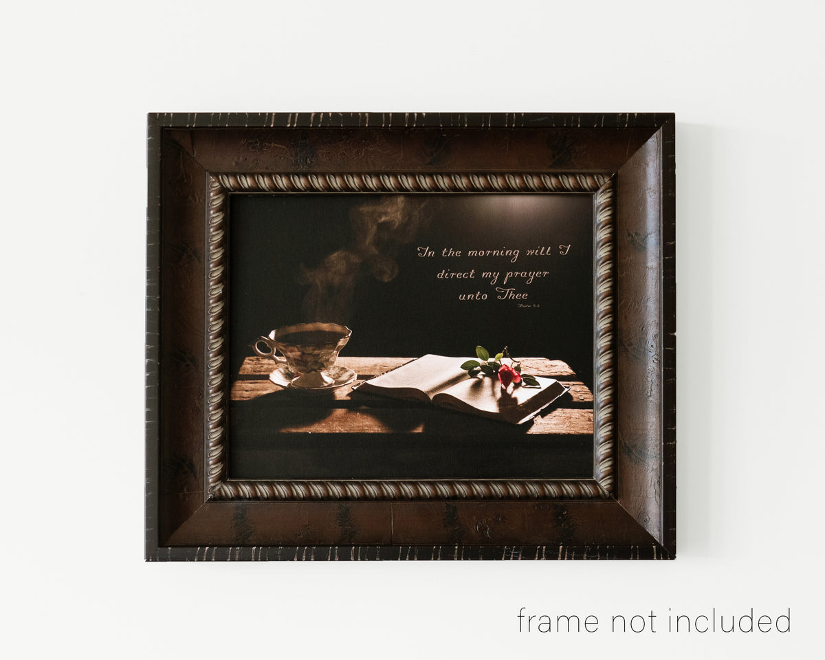 framed print of Steaming cup of coffee beside open Bible with scripture verse