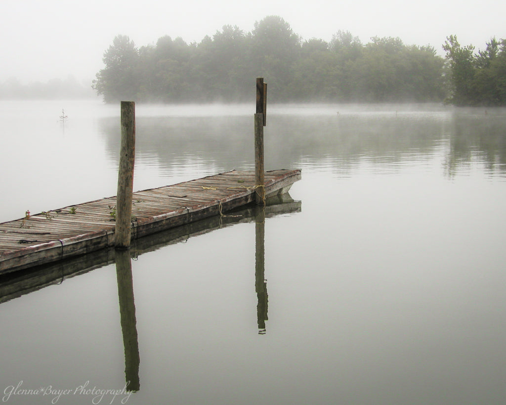 Old wooden dock over a lake on a foggy, gray morning.