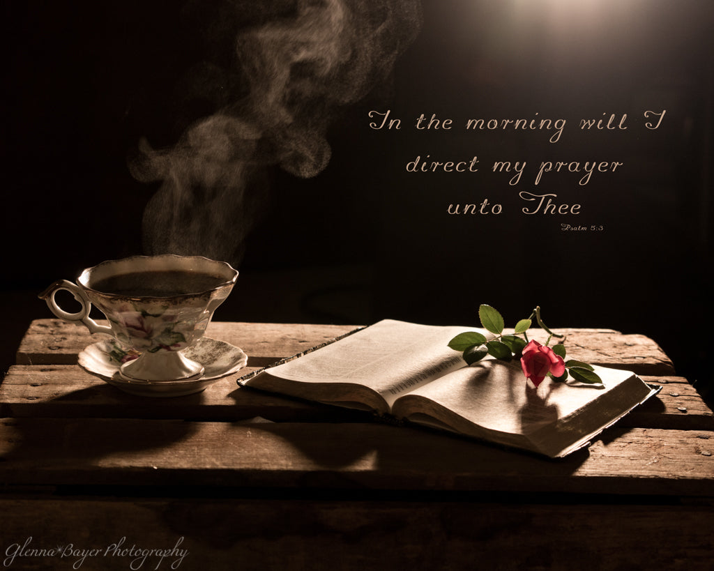 Steaming cup of coffee beside open Bible with scripture verse