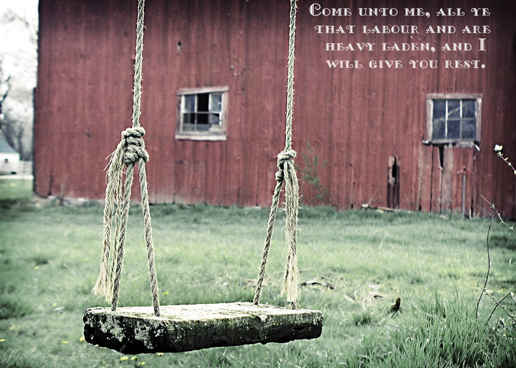 Old wooden rope swing and red barn with scripture verse