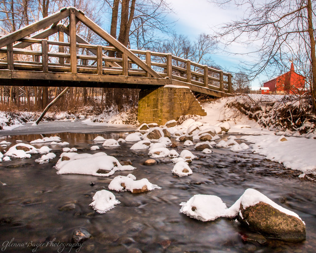 Snowy Stream, wooden bridge, and red barn at Carriage Hill Metro Park in Ohio